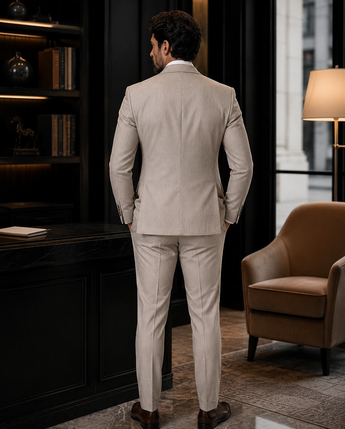 Barutti.ae beige pinstripe double-breasted suit worn by a man in a study, showing the back view of the tailored jacket.