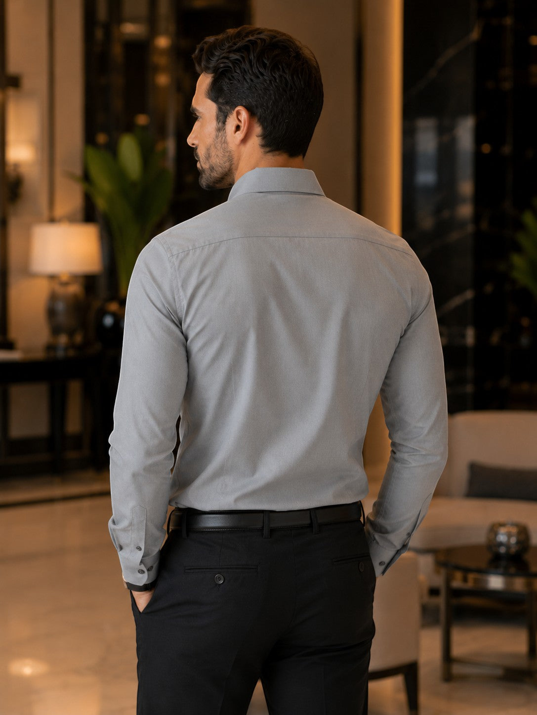 Back view of a man wearing a Barutti.ae grey birdseye textured modern-fit cotton shirt with black trousers.