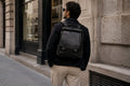 Man wearing a black Barutti leather commuter backpack on a city street.