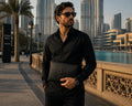 Man in black shirt holding a Barutti Milano black pebbled leather zip clutch with croc-embossed band
